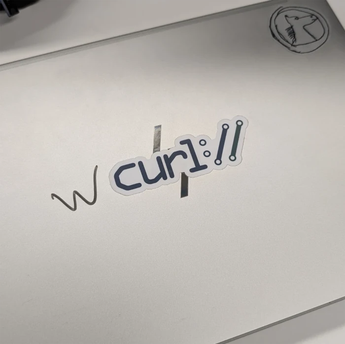 A laptop with a curl and a GoHorse
sticker, there's a 'w' handwritten with a marker on the right side of the curl
sticker, making it 'wcurl'